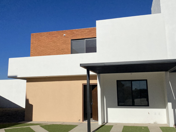 Fachada frontal de la casa modelo Amada en Fraccionamiento Antequera, Pozos, San Luis Potosí, con jardín y entrada principal.