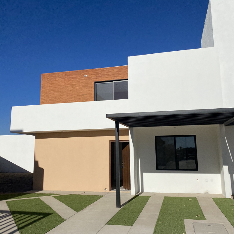 Fachada frontal de la casa modelo Amada en Fraccionamiento Antequera, Pozos, San Luis Potosí, con jardín y entrada principal.