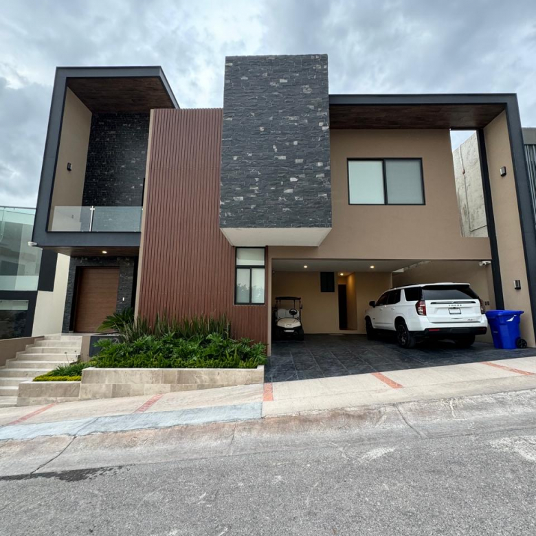 Fachada moderna de casa en La Loma Residential & Golf Club con vistas a la ciudad y jardín iluminado.