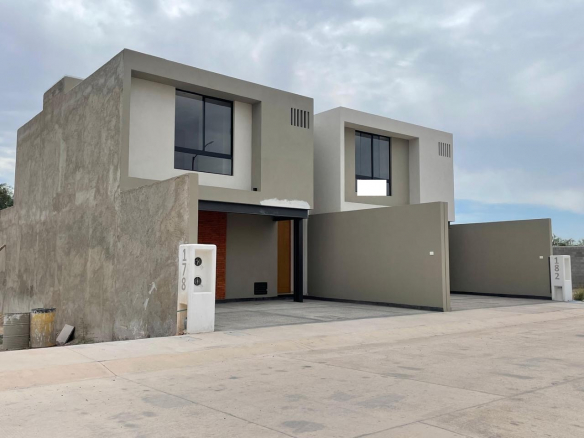 Fachada de casa de 2 plantas en Privada Zibari, Pozos, SLP — cochera 2 autos, jardín y acabados en mármol y granito.