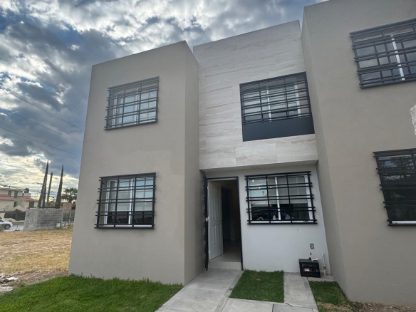 Fachada moderna de casa en venta construida con ladrillo rojo y cochera para dos autos en colonia La Nueva Herradura.