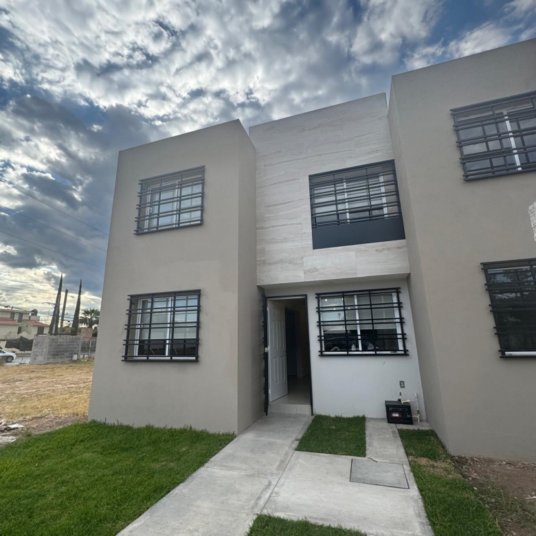 Fachada moderna de casa en venta construida con ladrillo rojo y cochera para dos autos en colonia La Nueva Herradura.