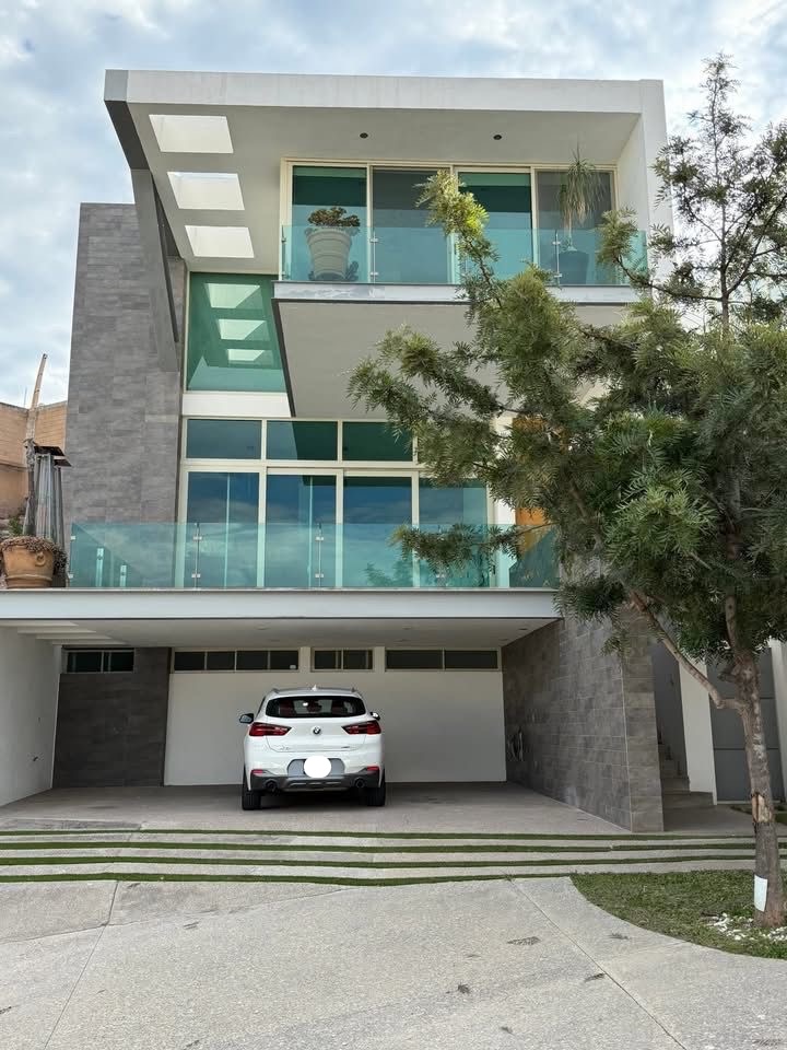 Casa moderna de tres niveles en Pedregal 2 con fachada de piedra volcánica, amplios ventanales y cochera para 3 autos.
