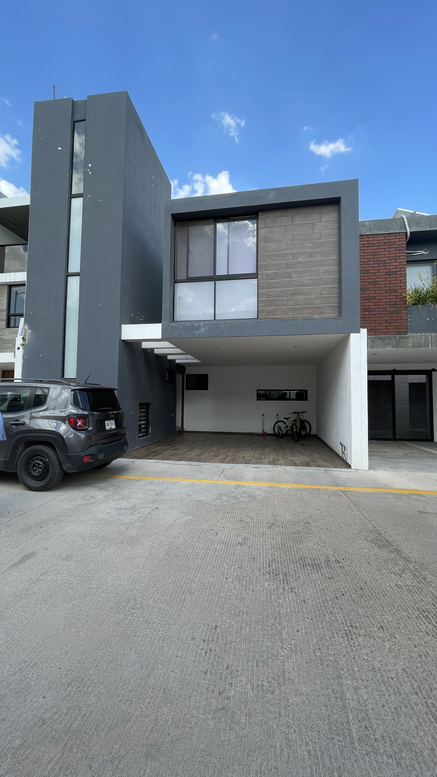 Casa moderna de tres niveles con fachada gris y acabados tipo madera en Cimera Residencial, Mexquitic de Carmona, SLP.