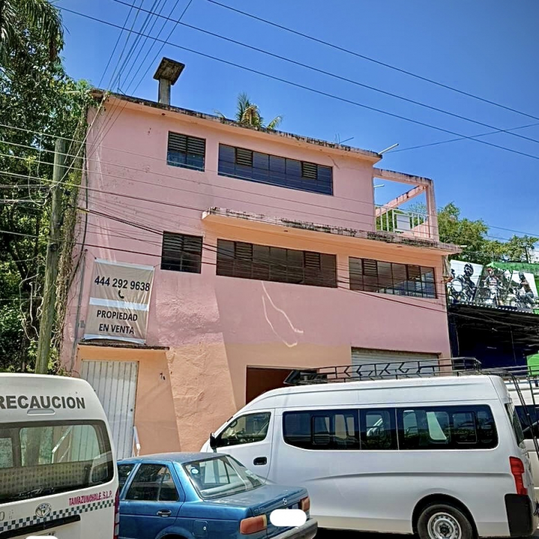 Edificio comercial de tres plantas en venta ubicado en Blvd. 20 de Noviembre, Tamazunchale, SLP. Fachada color rosa con lona de venta y ventanas amplias.
